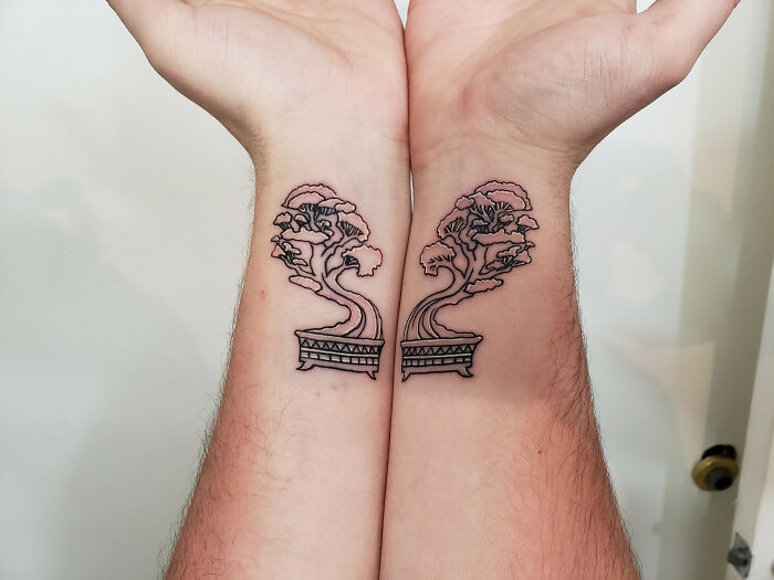 Matching tree tattoos on forearms celebrate nature's wonders, showcasing intricate designs in a minimalist style.