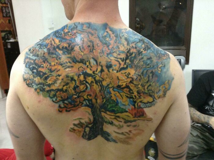 Back tattoo of a colorful majestic tree, showcasing intricate branches and leaves, celebrating the wonders of nature.