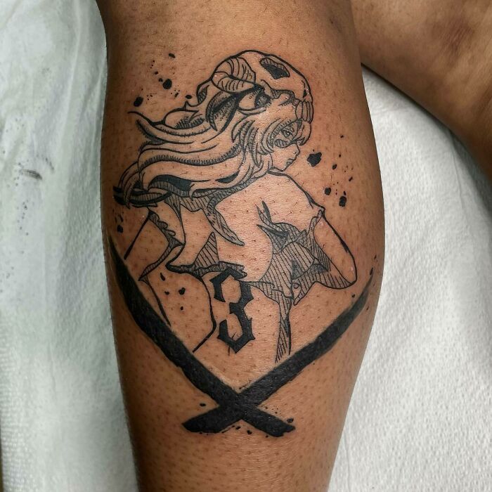 Anime tattoo featuring a character with horns and a cloak, surrounded by ink splatters and crossed swords on the leg.