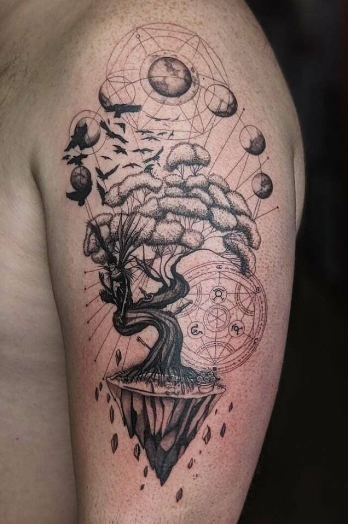 Anime tattoo of a mystical tree with planetary and geometric patterns on an arm.