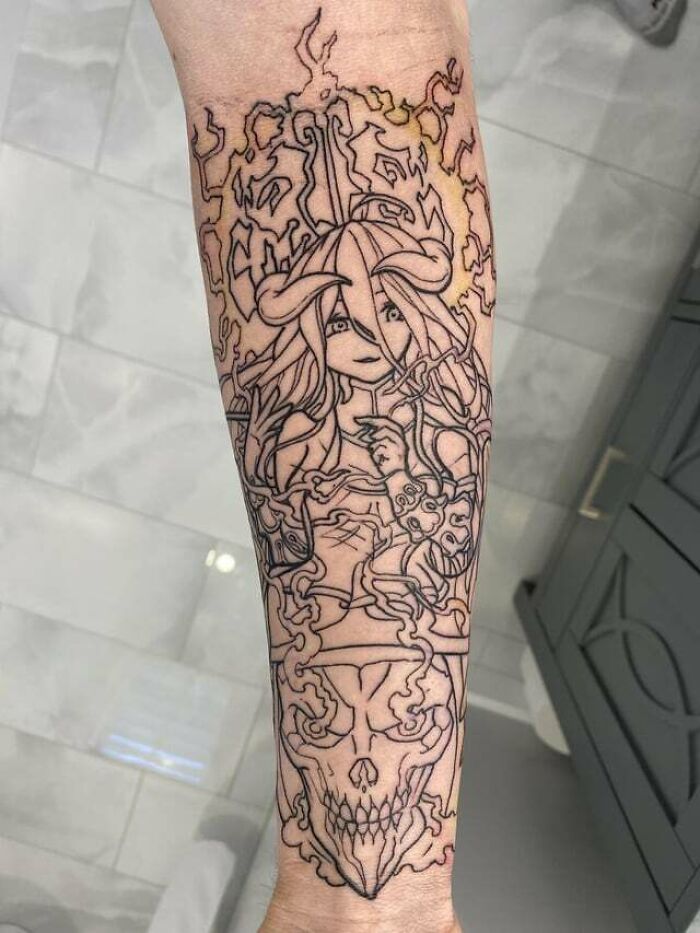 Anime tattoo with intricate line art featuring a female character with horns and a menacing skull below.