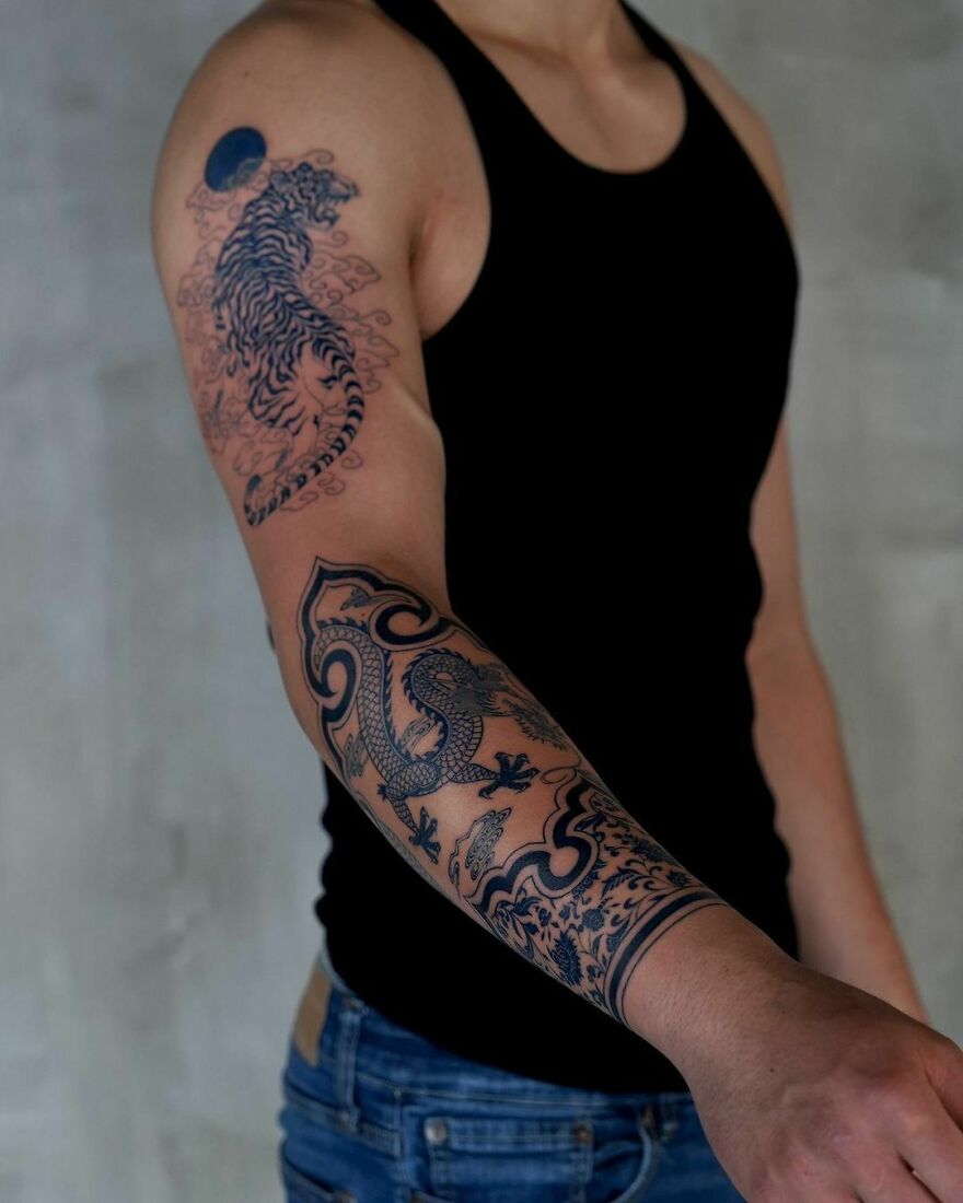 Dragon tattoo on a person's arm, featuring intricate black ink designs and patterns.