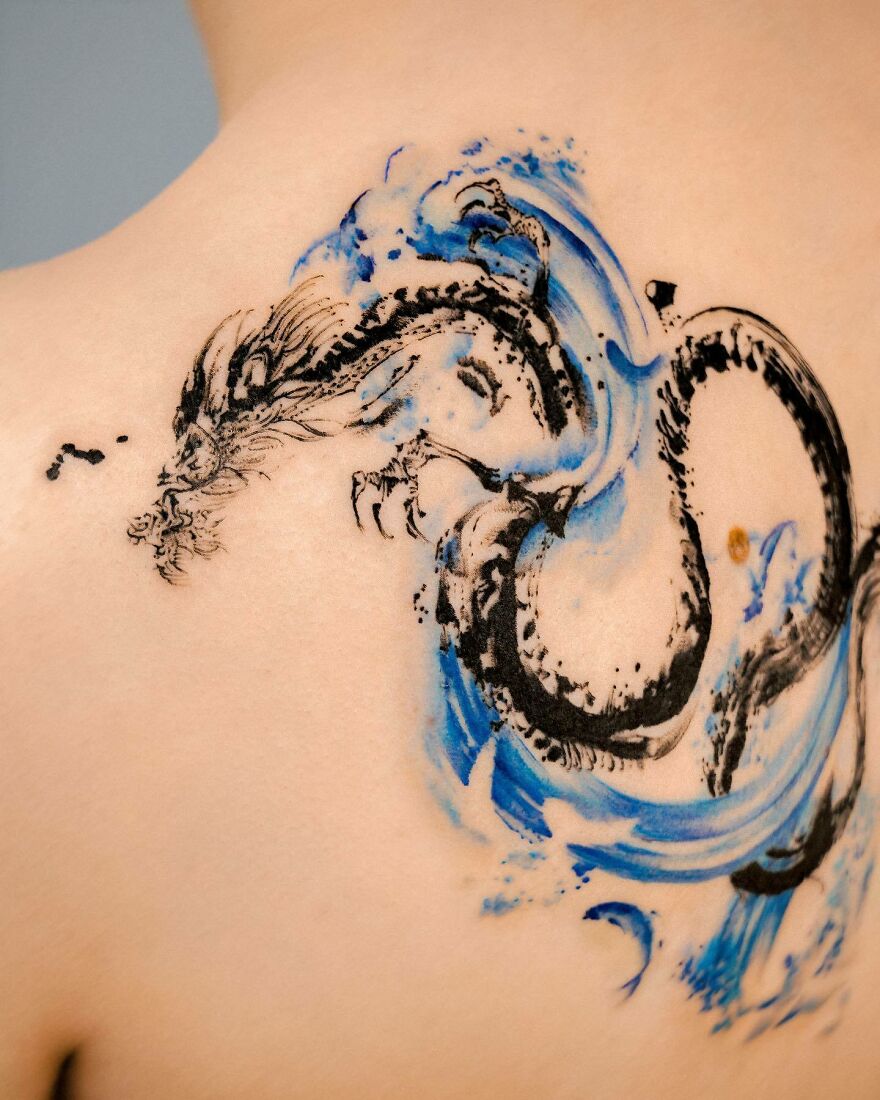 Black and blue dragon tattoo design on a person's back, showcasing intricate and fluid artwork.