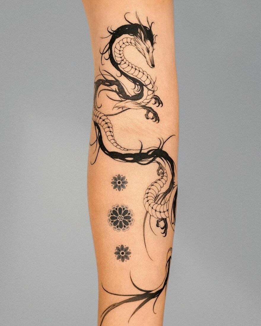 Dragon tattoo design on forearm with intricate details and floral accents.