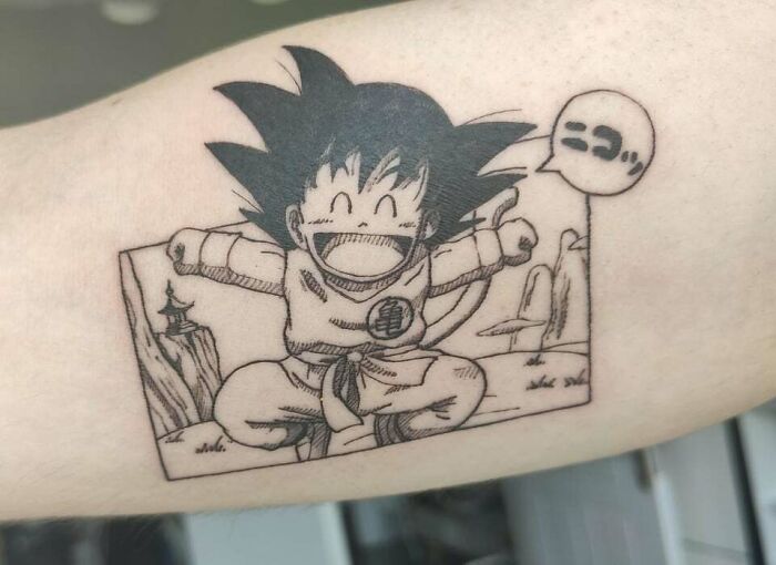 Anime tattoo featuring a joyful character with spiky hair and an expressive speech bubble on an arm.