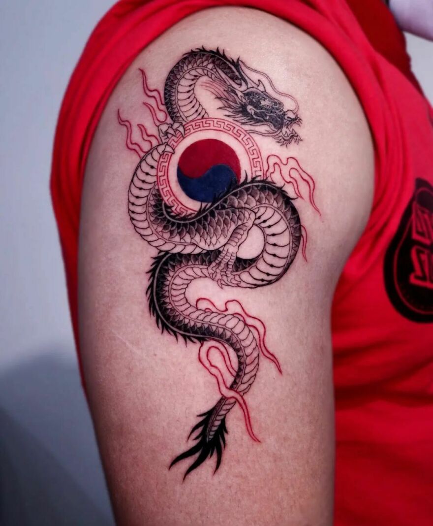 Dragon tattoo design on upper arm, featuring intricate scales and a central yin-yang symbol with red accents.