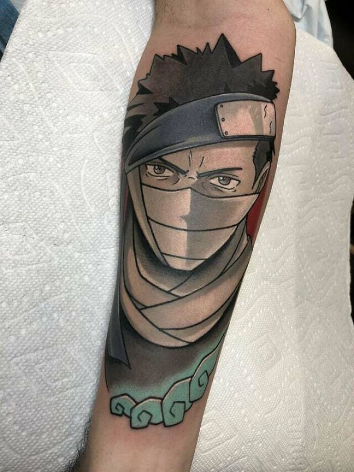 Anime tattoo of masked character on forearm, featuring bold lines and muted colors, showcasing cool tattoo artistry.