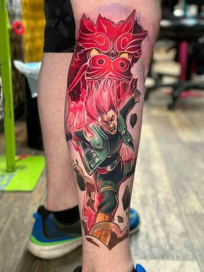 Anime tattoo on leg featuring a dynamic character with red energy and a fierce creature in a colorful design.