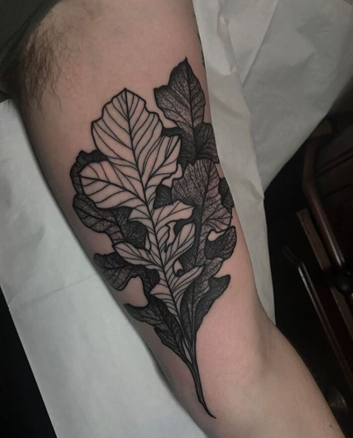 Tattoo of intricate leaves on skin, showcasing majestic tree design.