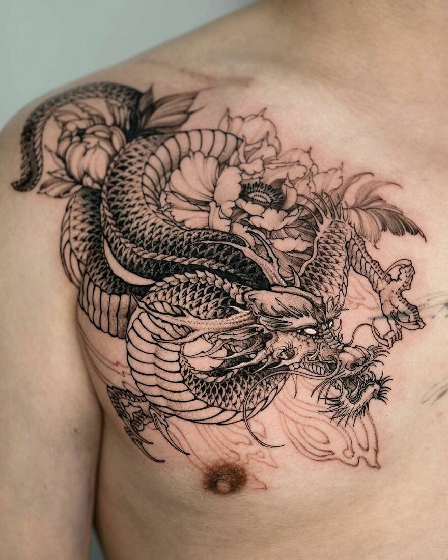Intricate black dragon tattoo design on a person's shoulder and chest, featuring floral accents.