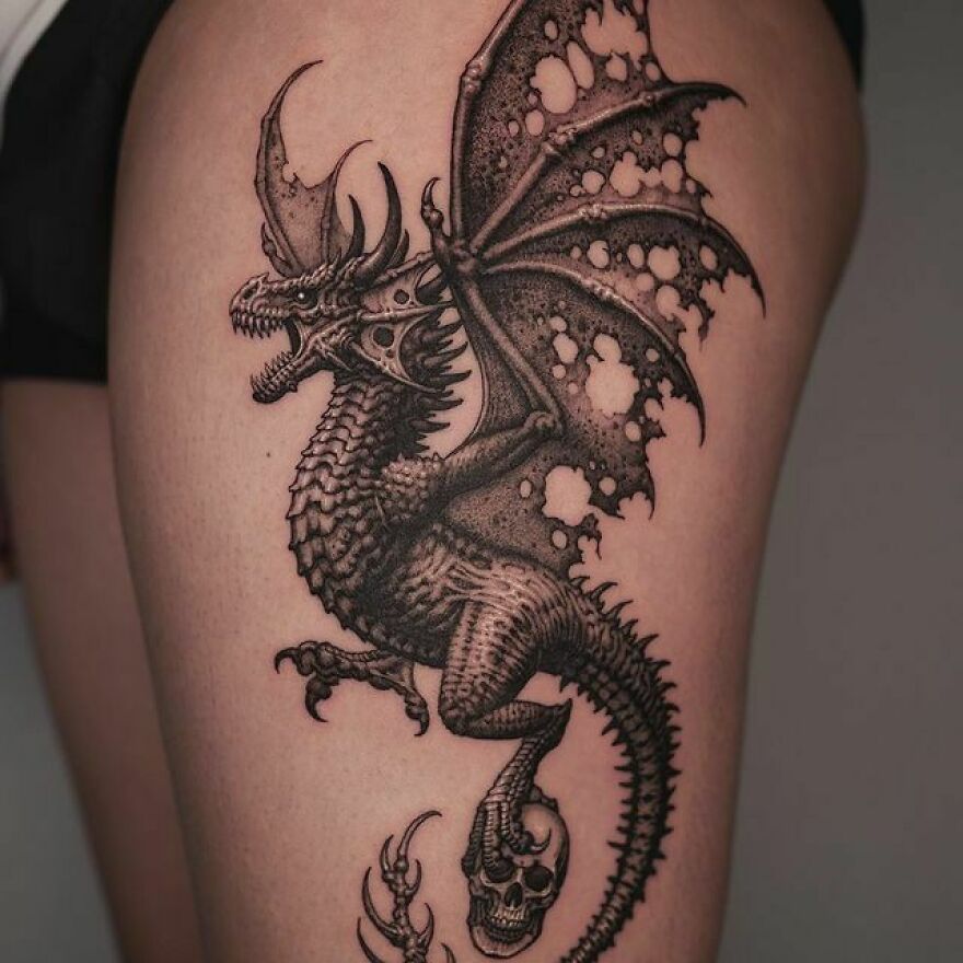 Dragon tattoo design featuring detailed scales and wings on the thigh.