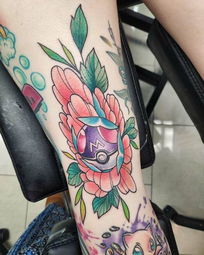 Anime tattoo featuring a Master Ball encircled by vibrant flowers on a person's leg.