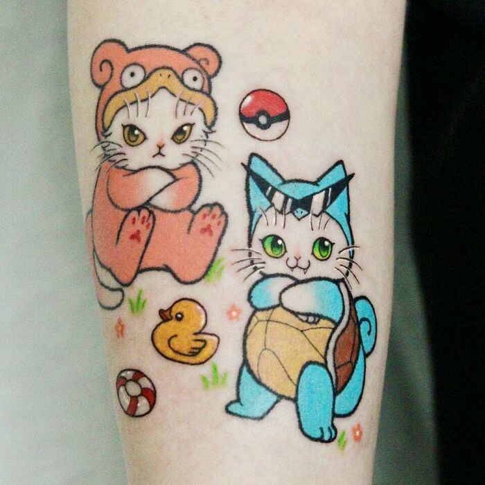 Anime tattoo of cute cats in Pokémon costumes with a Poké Ball and rubber duck accents.