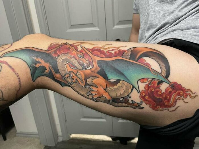 Anime tattoo of a dragon with fiery details on a person's leg.
