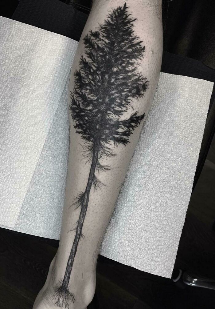 Black tree tattoo on forearm showcasing nature-inspired art.