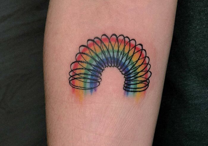 Colorful slinky tattoo on forearm, inspired by '90s culture.