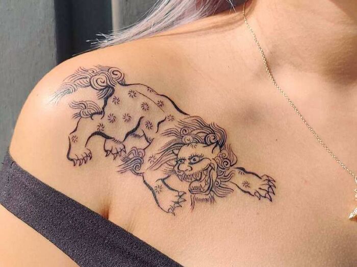 Lion tattoo on a woman's collarbone with intricate linework, showcasing a stunning design for men and women.