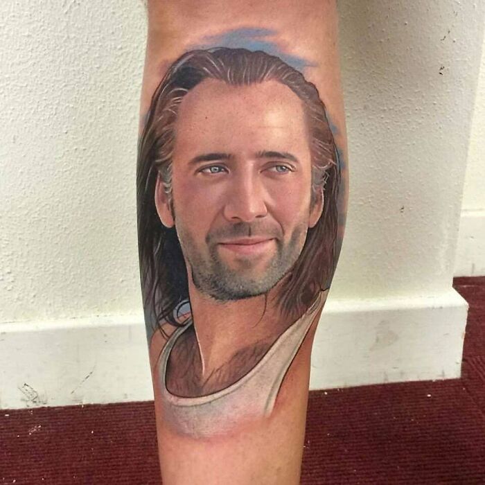 Realistic ‘90s tattoo of a man with long hair and a white tank top on a calf.