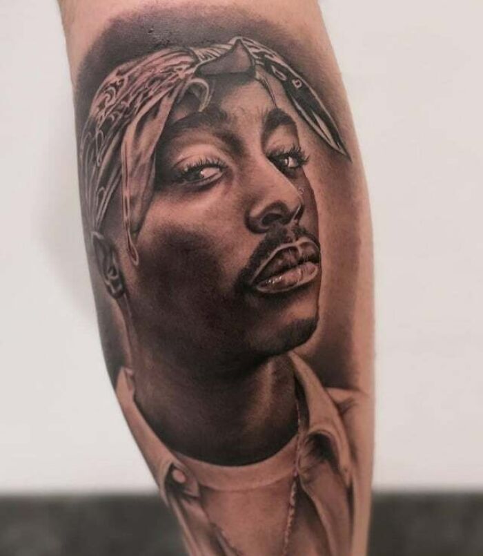 ‘90s tattoo featuring iconic cultural portrait on forearm.