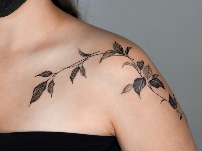 Elegant leaf collarbone tattoo design on a woman's shoulder, showcasing intricate black ink details.