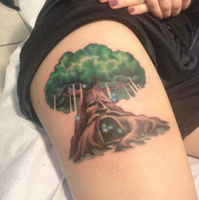 Majestic tree tattoo on a thigh, showcasing intricate details and vibrant colors.