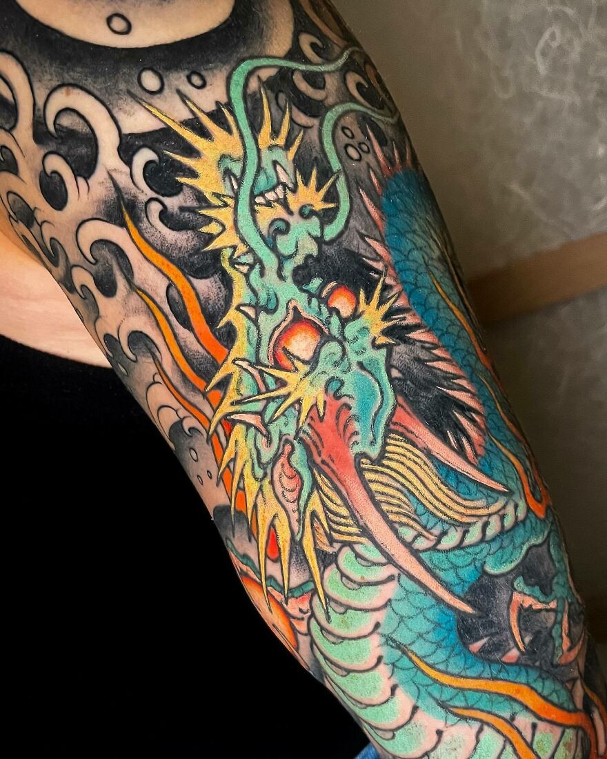 Vibrant dragon tattoo on an arm, featuring bold colors and intricate details, showcasing dragon tattoo ideas.