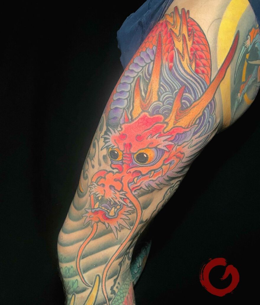 Colorful dragon tattoo on arm, vibrant design showcasing fiery elements and intricate details.