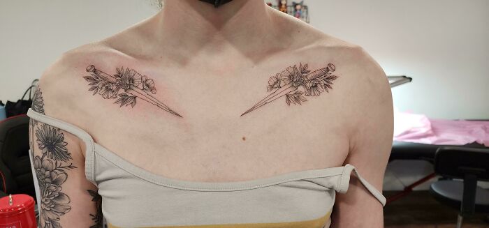 Floral collarbone tattoos on a person wearing a strapless top in a tattoo studio setting.