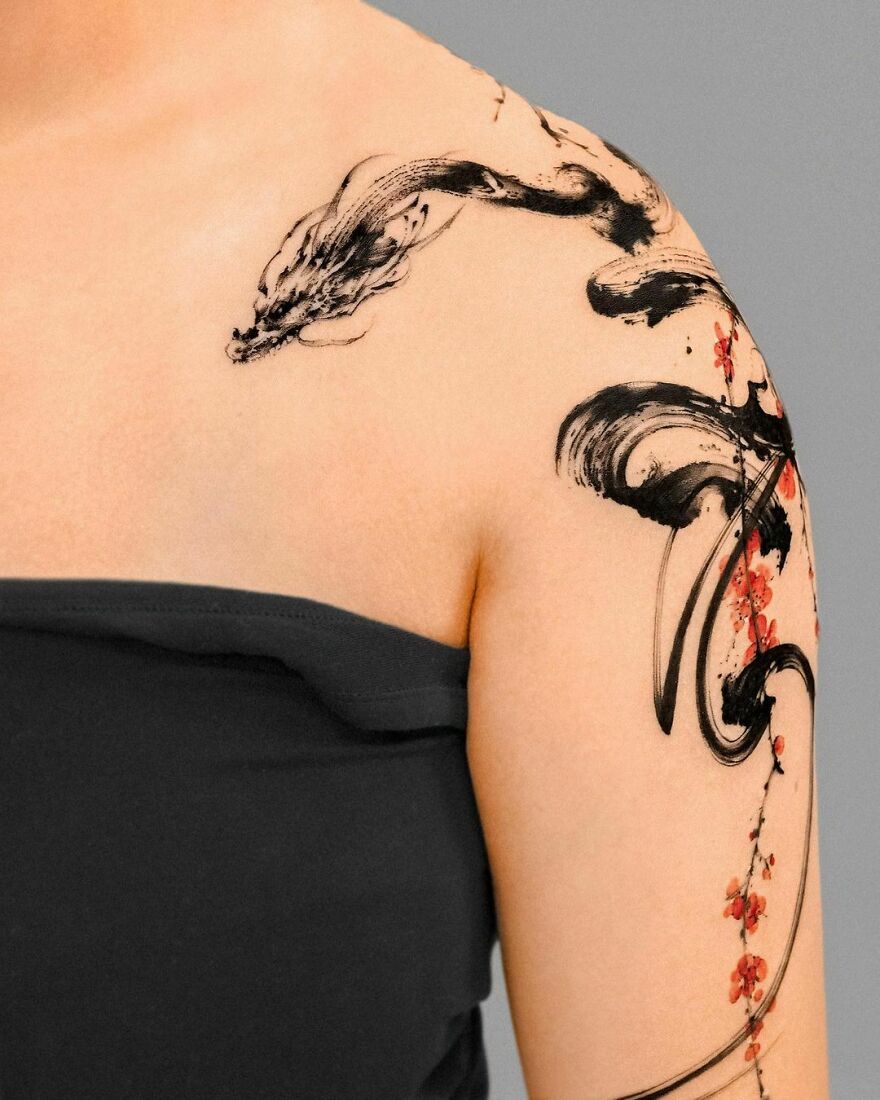 Dragon tattoo on shoulder, intricate design with black ink and floral accents.