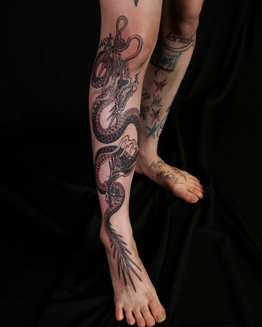 Leg featuring an intricate dragon tattoo design, showcasing detailed black ink artistry.