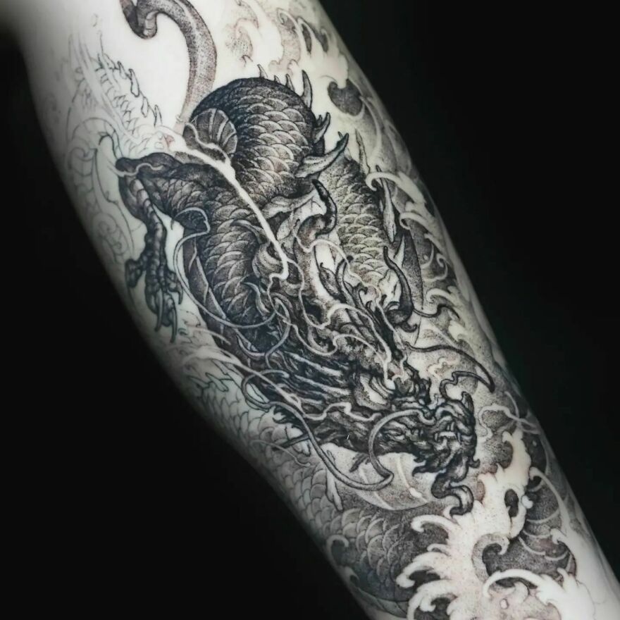 Intricate black-and-white dragon tattoo design on forearm, featuring detailed scales and fierce expression.