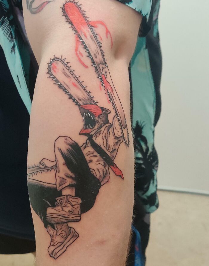 Anime tattoo with chainsaw character design on an arm, showcasing dynamic and colorful artwork.
