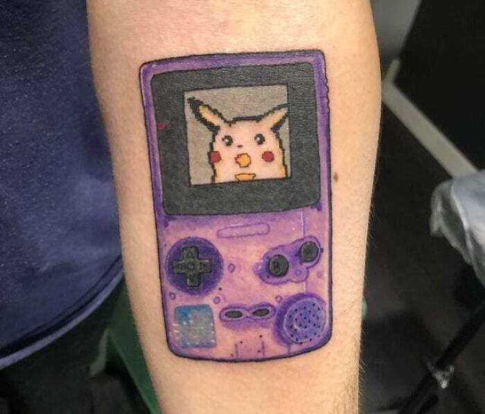 Anime tattoo of a vintage purple Game Boy with Pikachu on the screen, showcasing creative ink design.
