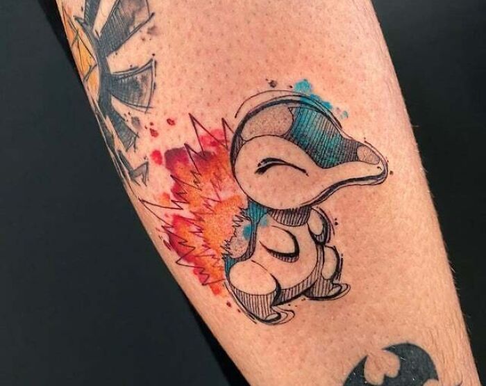 Watercolor anime tattoo of a fiery creature on an arm, showcasing vibrant colors and creative design.