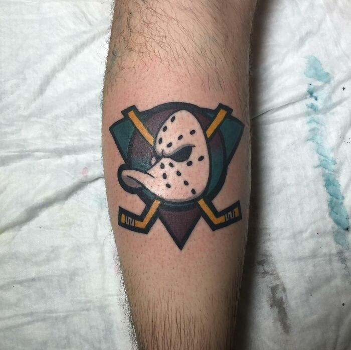 '90s tattoo featuring a vintage hockey mask with crossed sticks design on forearm.