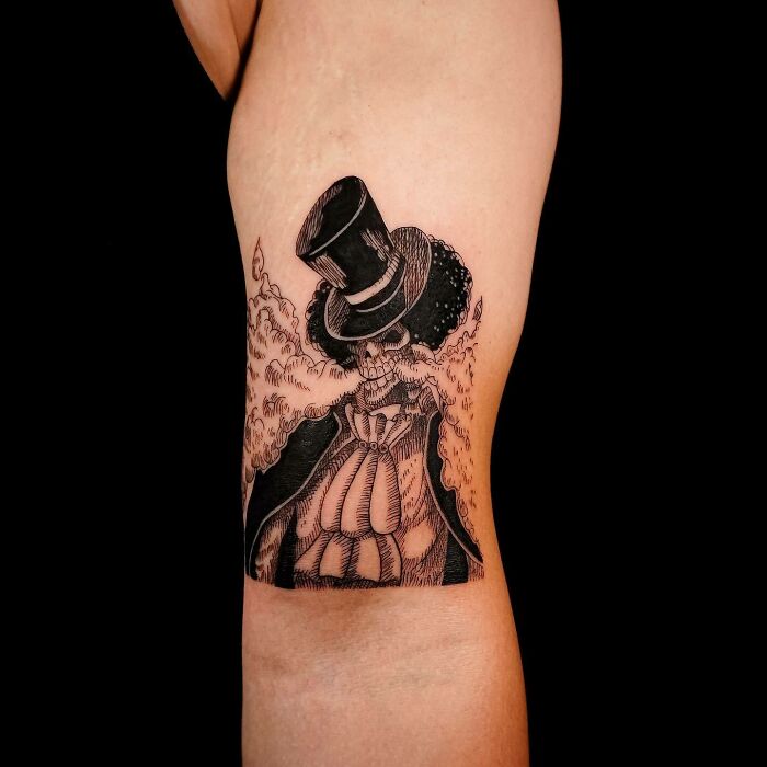 Tattoo of a skeleton in a top hat with detailed anime-style shading on a forearm.