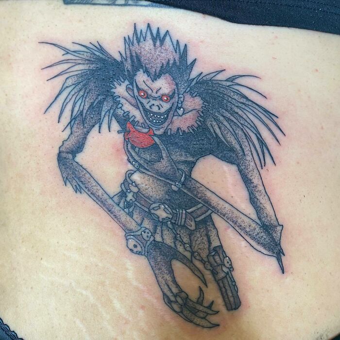 Anime tattoo featuring a detailed character with red eyes and distinct features, showcasing intricate ink artistry.