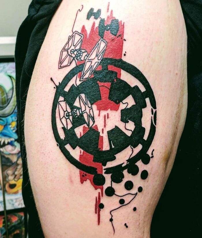 Trash polka tattoo design featuring black and red abstract elements and spaceships on skin.