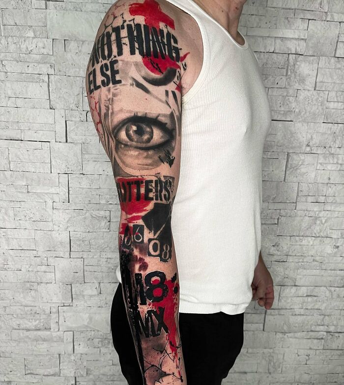 Man with a detailed Trash Polka tattoo sleeve featuring eye and text elements, wearing a white tank top.