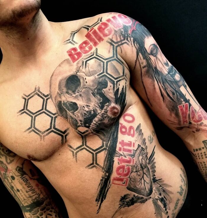 Trash polka tattoo featuring skulls, hexagons, and bold red text on a man's chest.
