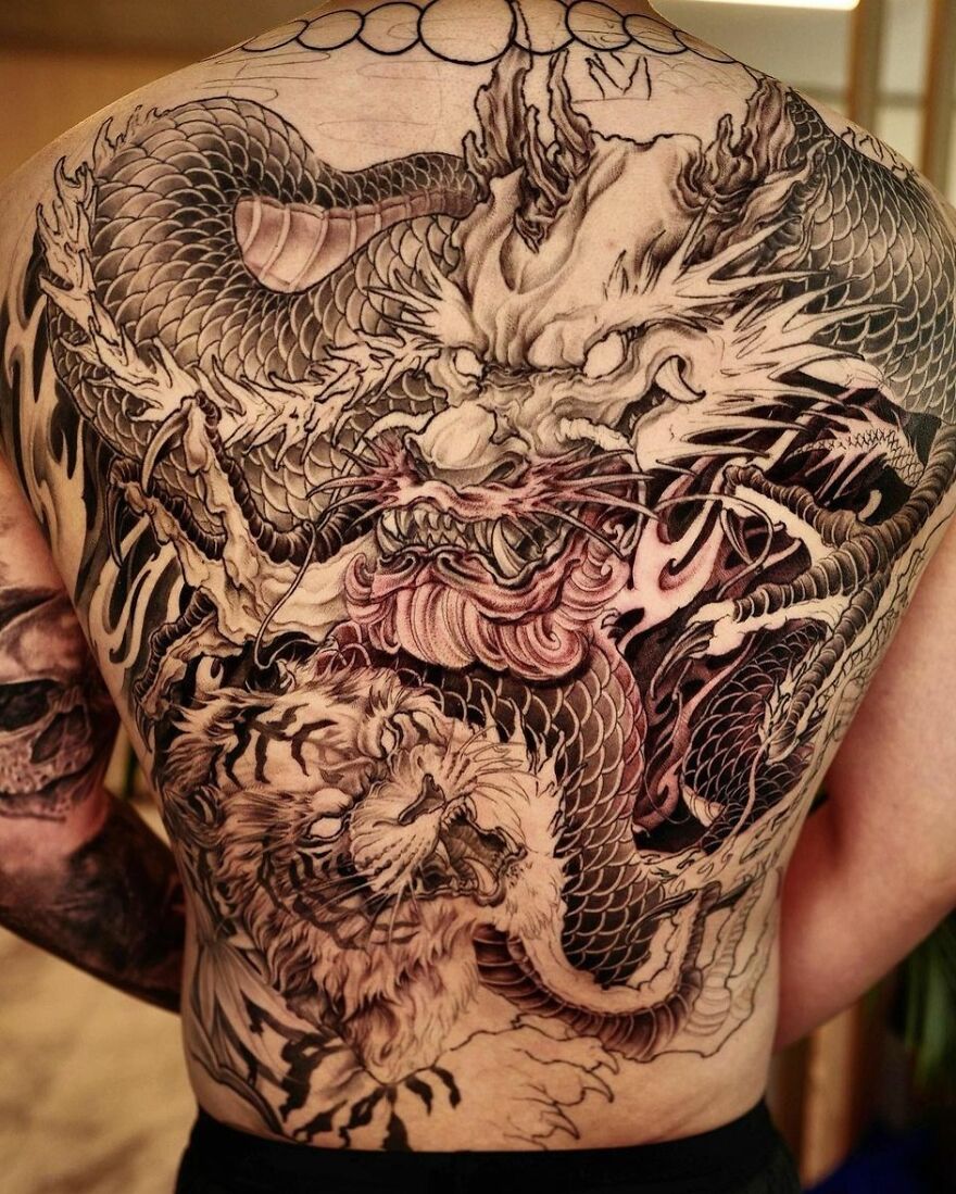 Intricate dragon tattoo covering a man's back, featuring scales and fierce detailing.