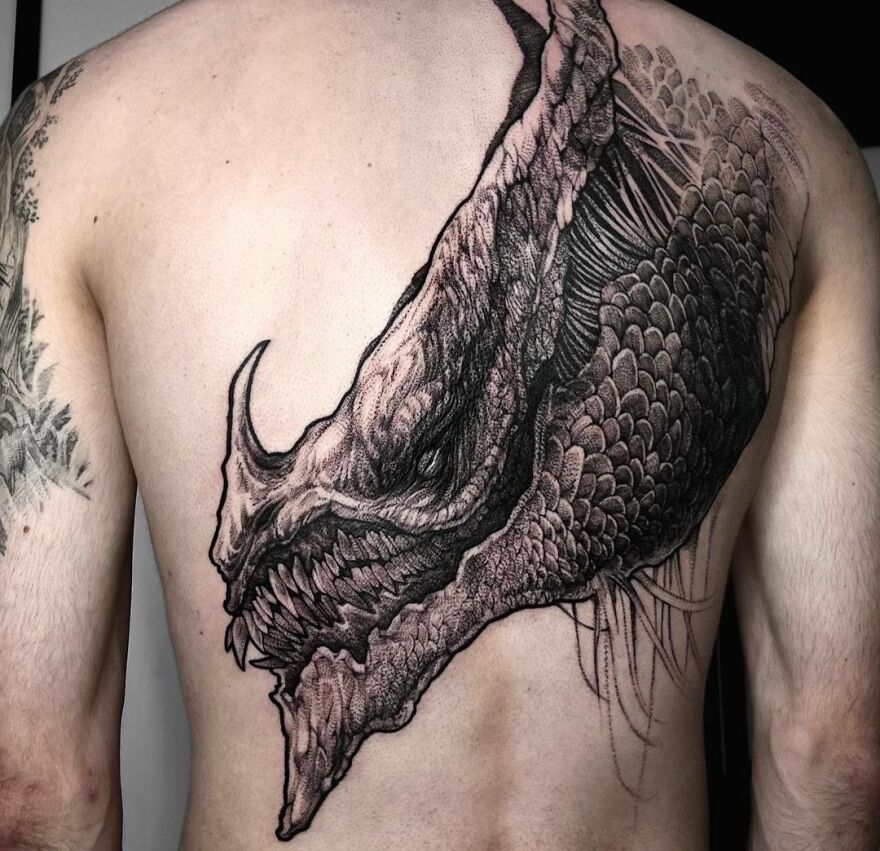 Detailed dragon tattoo covering a man's back, showcasing intricate scales and fierce expression.