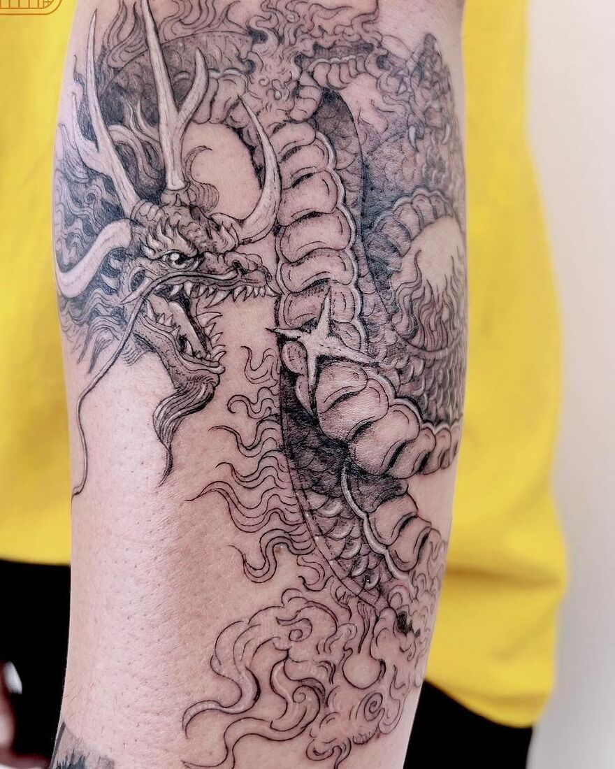 Dragon tattoo intricately designed on arm, showcasing detailed scales and fierce expression against a yellow background.