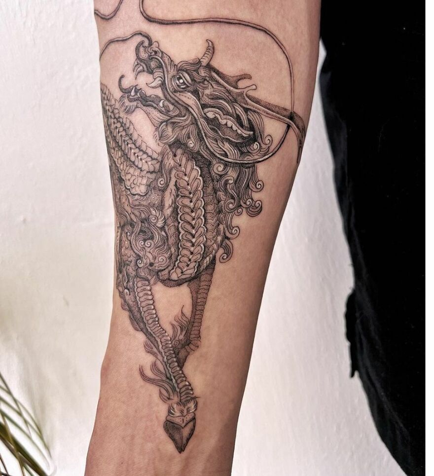 Intricate dragon tattoo design on forearm, showcasing detailed scales and fierce expression.
