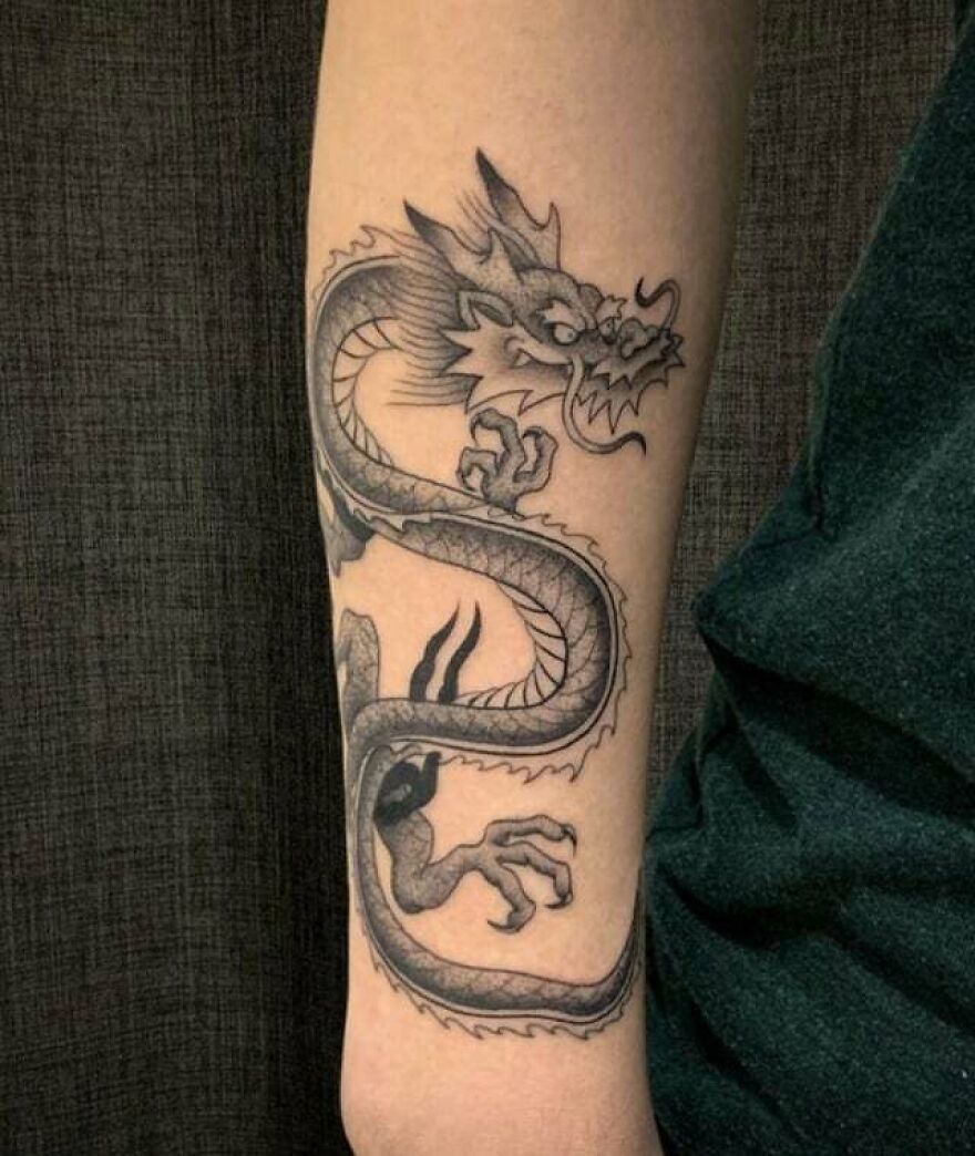 Dragon tattoo intricately inked on a forearm, showcasing detailed scales and fierce expression.