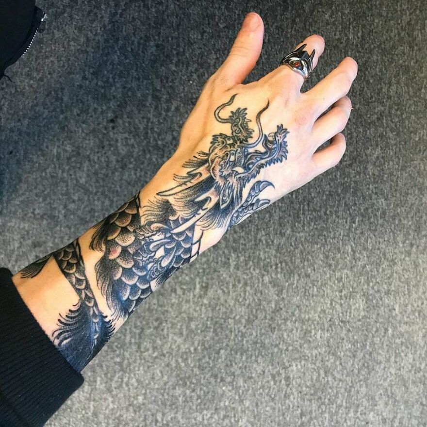 Dragon tattoo on a person's forearm, detailed black ink design showcasing scales and claws.
