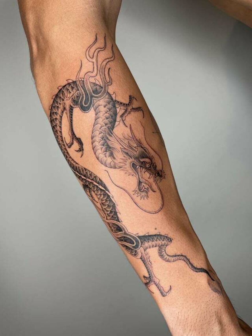Elegant dragon tattoo design on a forearm, showcasing intricate details and flowing lines.