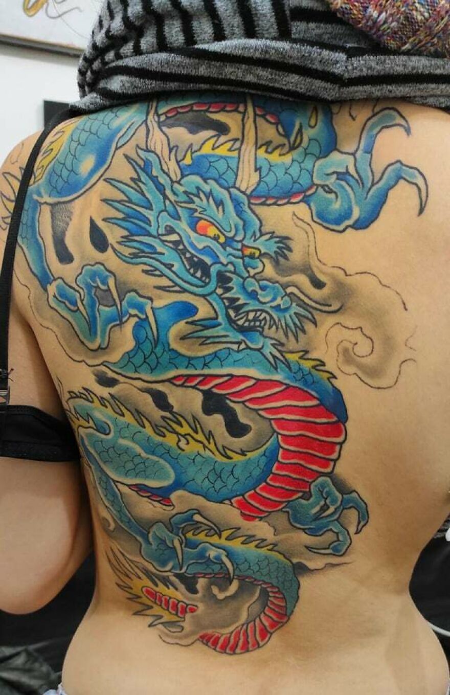 Vibrant dragon tattoo design with blue and red tones on a person's back.