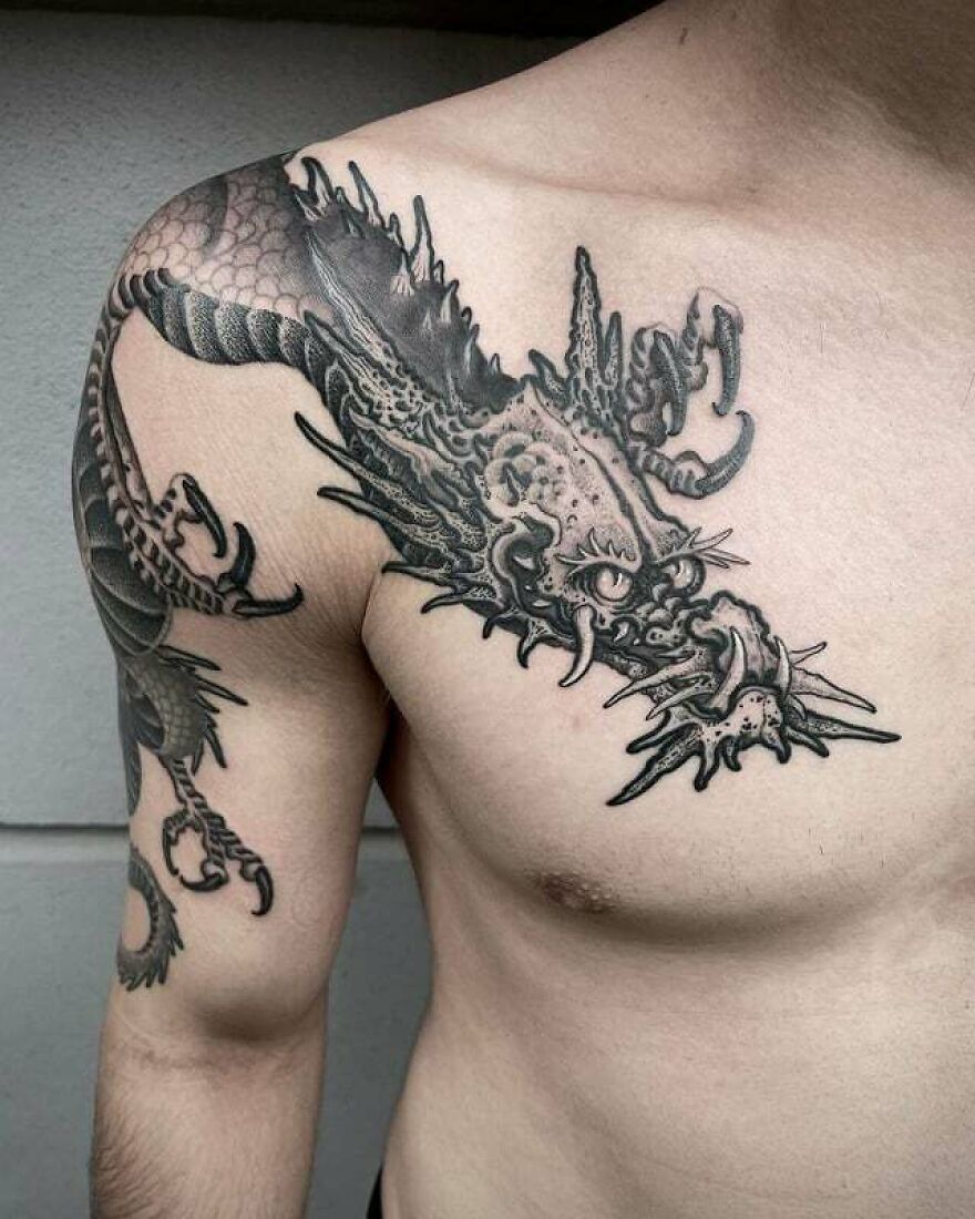 Close-up of a detailed dragon tattoo on a person’s shoulder and chest.