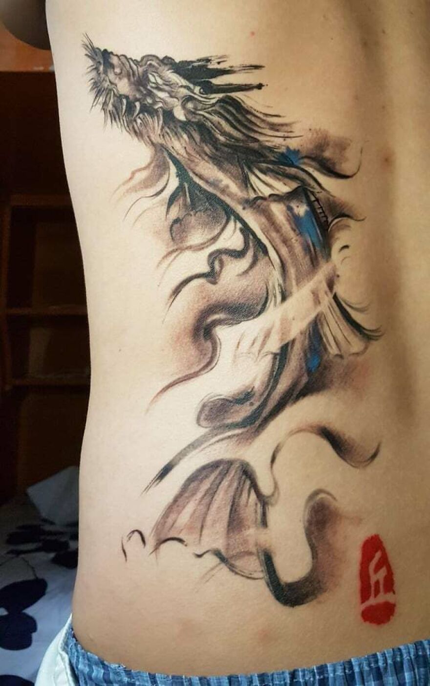 Intricate dragon tattoo design on side of torso, featuring bold black and blue ink details.